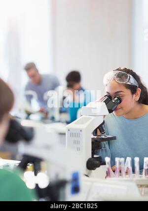 Girl student using microscope, conducting scientific experiment in laboratory classroom Stock Photo