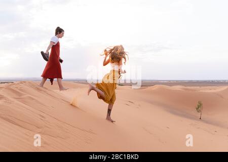 Two young women on sand dune in Sahara Desert, Merzouga, Morocco Stock Photo