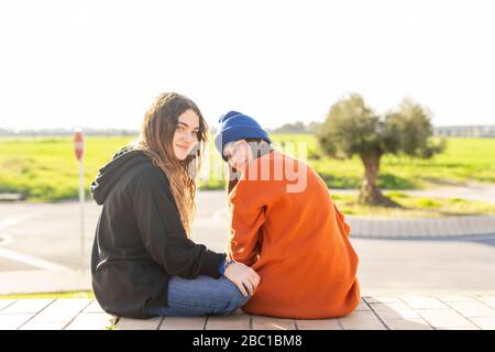 Portrait of two teenage girls sitting  outdoors Stock Photo