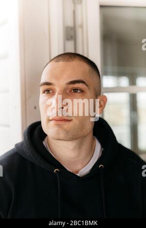 Portrait of pensive young man with shaved head looking at distance Stock Photo
