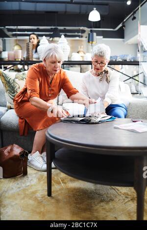 Senior women looking at fabric swatches in furniture store Stock Photo