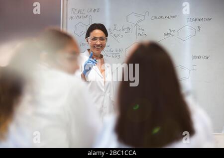 Smiling female science teacher leading lesson at whiteboard in classroom Stock Photo