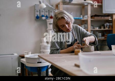 Young woman working on workpiece in pottery Stock Photo