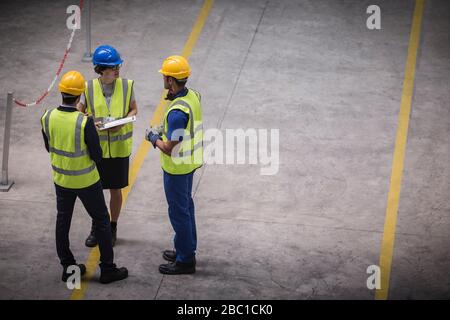 Supervisor and workers with clipboard talking in factory Stock Photo