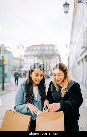 Two young women with shopping bags in the city, Lisbon, Portugal Stock Photo