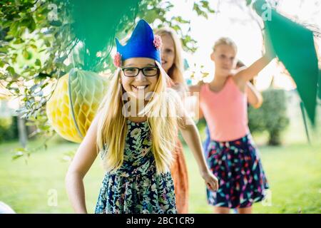 Portrait of happy girl wearing a party hat on a birthday party outdoors Stock Photo