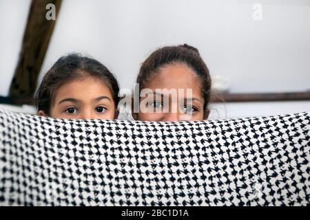 Portrait of mother and little daughter hiding behind lounge chair Stock Photo