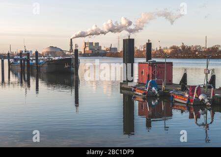 Germany, Hamburg, Boats moored on bank of Elbe river with Moorburg Power Plant in background Stock Photo