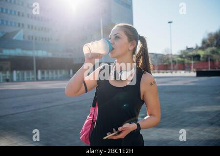 Sporty young woman drinking from cup in the city Stock Photo