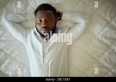 Portait of man in white shirt lying in bed Stock Photo