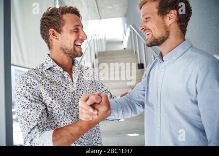 Portrait of two happy young businessmen shaking hands Stock Photo