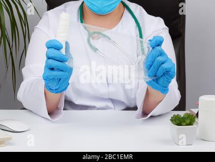 medic woman in white coat and mask holds a twisted gauze bandage for dressing wounds, white background Stock Photo