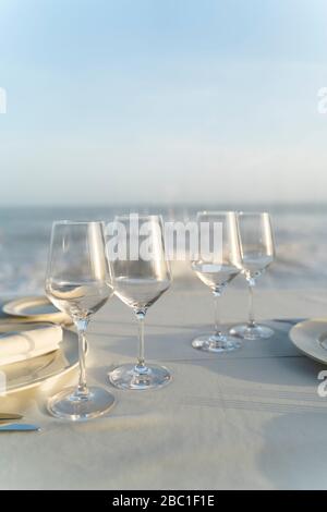 Spain, Empty wineglasses on set restaurant table with sea in background Stock Photo