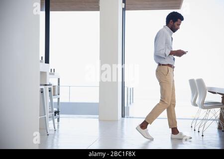Businessman texting, walking in dining room Stock Photo