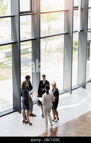 Business people standing in modern office building discussing project Stock Photo