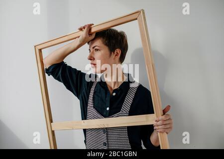 Portrait of a female painter holding a picture frame in her studio Stock Photo