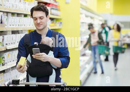 Father with baby scanning label on box in supermarket Stock Photo