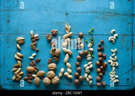 Overhead view of various nuts on blue rustic table Stock Photo