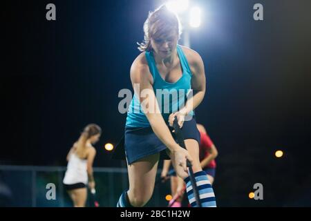Determined young female field hockey player practicing sports drill Stock Photo