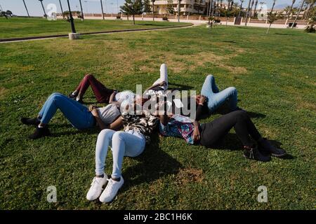 Teenage girlfriends and young man lying on a meadow together Stock Photo