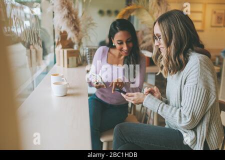 Two women using smartphones in a cafe Stock Photo