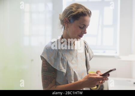 Woman with tattoos texting with smart phone Stock Photo
