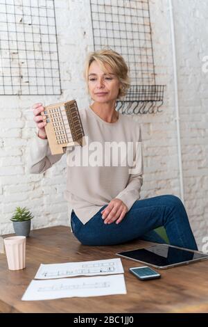 Mature woman at work sitting on desk in architectural office Stock Photo