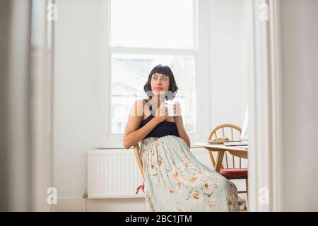 Thoughtful pregnant woman drinking tea in apartment Stock Photo