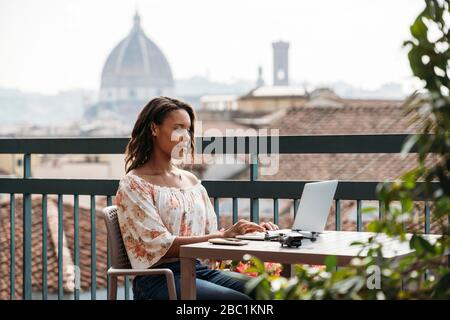 Young woman using laptop on a balcony in Florence, Italy Stock Photo