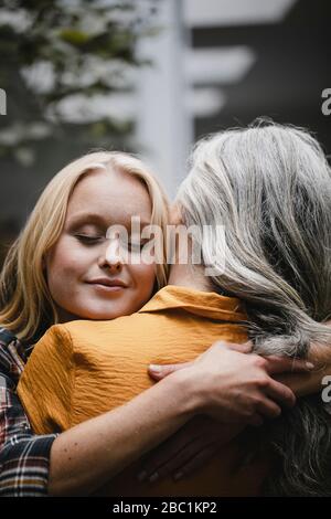 Portrait of adult daughter embracing mother outdoors Stock Photo