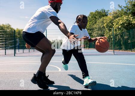 Father and son playing basketball on basketball court Stock Photo