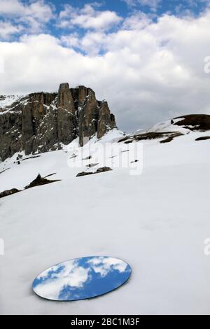 Mirror lying in snow, reflecting the sky at the Sella group in winter, Dolomites, Alto Adige, Italy Stock Photo