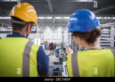 Supervisors talking and pointing on platform in factory Stock Photo