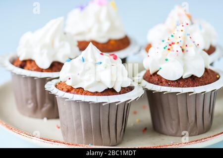Carrot cake cupcakes with cream cheese frosting with sprinkles. Close up. Stock Photo