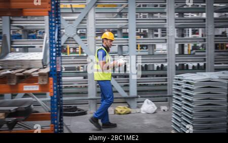 Male supervisor with clipboard checking inventory in steel warehouse Stock Photo