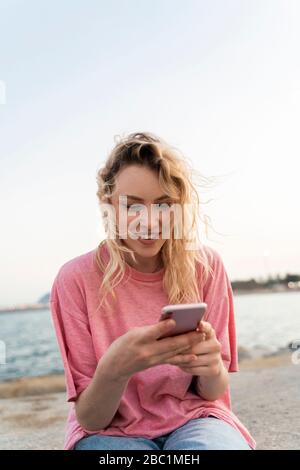 Young woman using smartphone at the waterfront Stock Photo