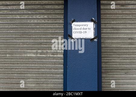 Metal hoardings on closed business premises and a Covid 19 temporary closure sign during the coronavirus outbreak. Northfield Avenue, Ealing, London Stock Photo