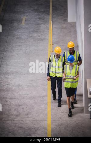 Supervisor and workers with digital tablet walking in factory Stock Photo