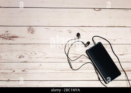 Top view smartphone mockup mobile Blank screen smartphone with earphone on wooden rustic table Stock Photo