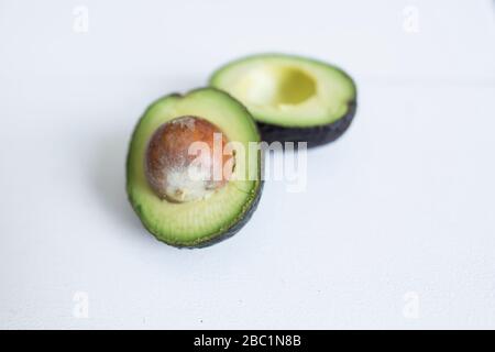 A sliced in half fresh, green avocado with the pit inside ready to be used in a snack or meal. Stock Photo
