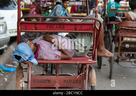 Driver sleeping on his cycle rickshaw in Old Delhi, India Stock Photo