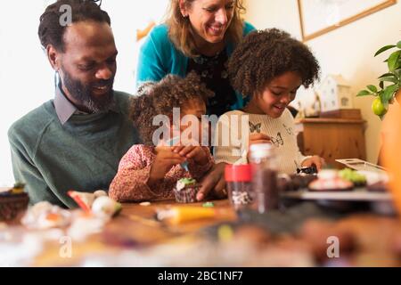 Family decorating cupcakes at table Stock Photo