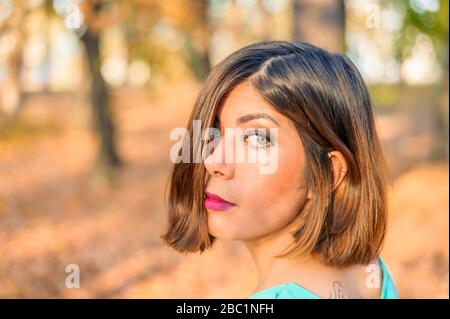face of a beautiful young black-haired woman half-covered by hair in a yellow autumn forest Stock Photo