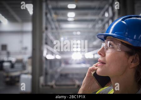 Female worker talking on cell phone in factory Stock Photo
