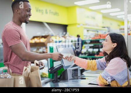 Cashier giving receipt to customer at supermarket checkout Stock Photo