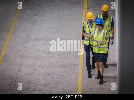 Female supervisor and male workers walking and talking in factory Stock Photo