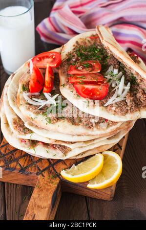 Lahmacun Turkish traditional cuisine, flatbread with minced meat and spices. Usually served with lot of greens tomatoes lemon and ayran. Stock Photo