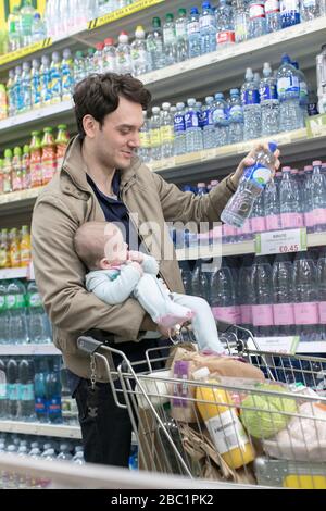 Father with baby daughter grocery shopping in supermarket Stock Photo