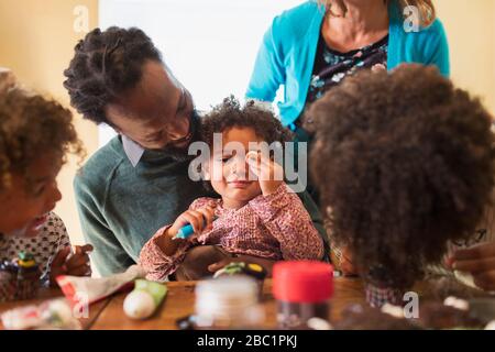 Family decorating cupcakes at table Stock Photo