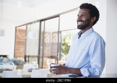 Smiling man drinking coffee, looking away Stock Photo
